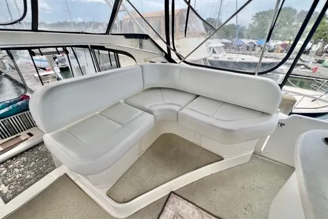 Slide: The Image of 2003 Silverton 43 Motor Yacht interior with white cushioned seating in a marina setting. - 8