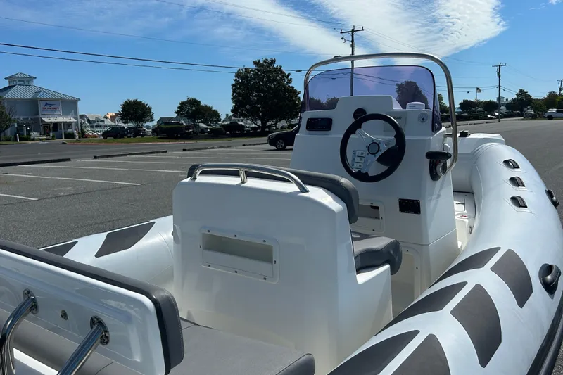 Slide: The Image of 2016 Brig Navigator 520 inflatable boat in parking lot, showcasing steering console and seating. - 14