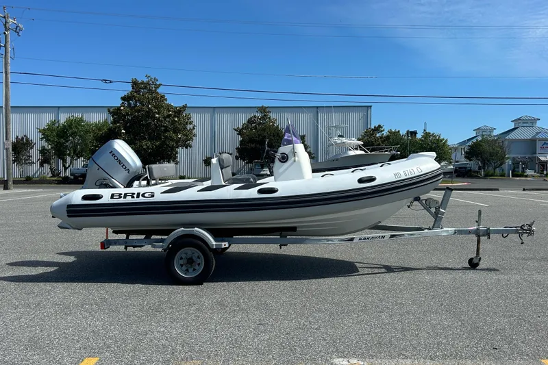 Slide: The Image of 2016 Brig Navigator 520 boat on trailer, parked in a lot under clear blue sky. - 5