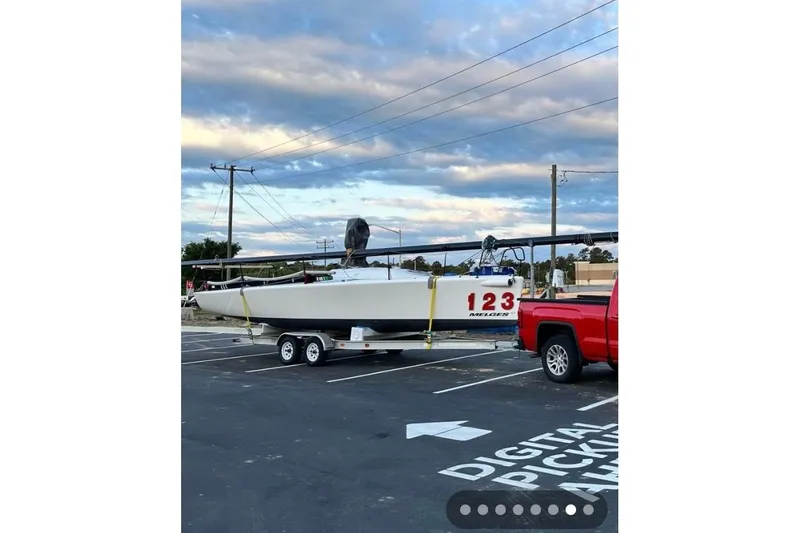 Slide: The Image of Red truck towing a 2005 Melges 32 sailboat on a trailer in a parking lot. - 5