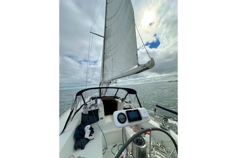 Slide: The Image of Sailing on a 1993 Ericson 38-200 yacht under cloudy skies, showcasing the helm and sails. - 10