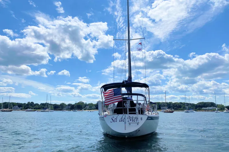 Slide: The Image of Sailboat Ericson 38-200 (1993) on water, American flag, blue sky, and clouds. - 2