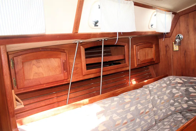 Slide: The Image of Interior of a 1991 Ericson 380 sailboat featuring wooden cabinetry and patterned seating. - 37