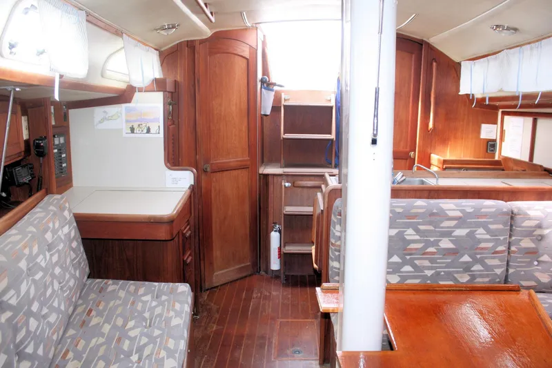 Slide: The Image of Interior of a 1991 Ericson 380 sailboat, featuring wood finishes and patterned seating. - 39
