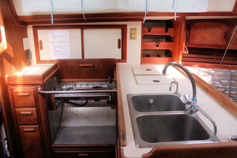 Slide: The Image of 1991 Ericson 380 yacht kitchen with dual sinks, stove, and wooden cabinetry. - 44