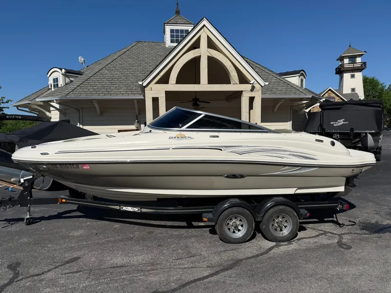 The Image of 2006 Sea Ray 200 Sundeck boat on trailer in front of building. - 1