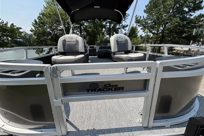 Slide: The Image of 2026 Sun Tracker Bass Buggy 18 DLX pontoon boat with seating, docked by trees. - 5