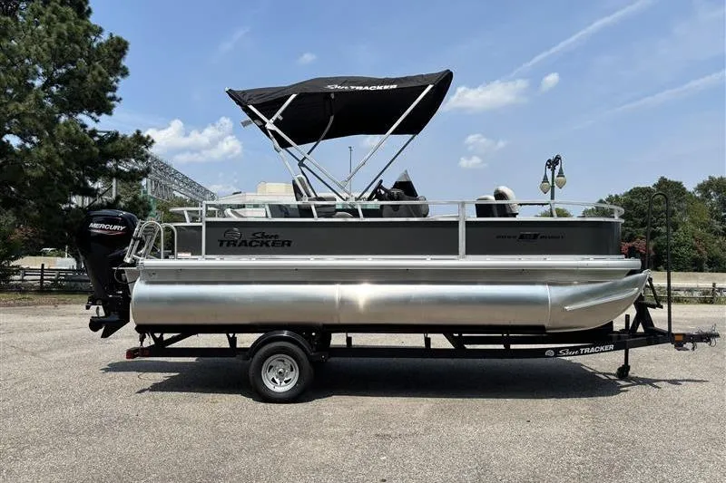Slide: The Image of 2026 Sun Tracker Bass Buggy 18 DLX pontoon boat on trailer, parked outdoors. - 3
