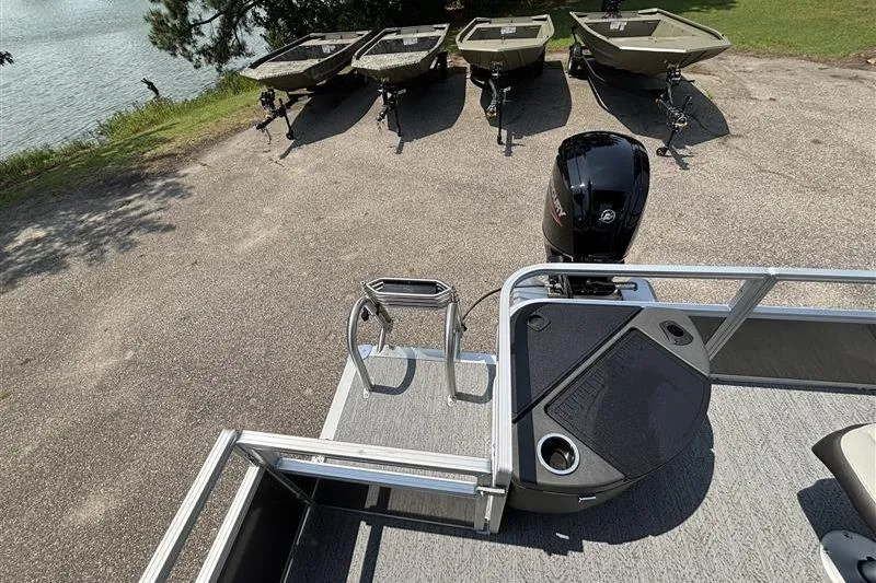 Slide: The Image of 2026 Sun Tracker Bass Buggy 18 DLX pontoon boat with motor, docked near small boats. - 26