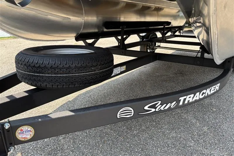 Slide: The Image of 2026 Sun Tracker Bass Buggy 18 DLX trailer with spare tire on pavement. - 4