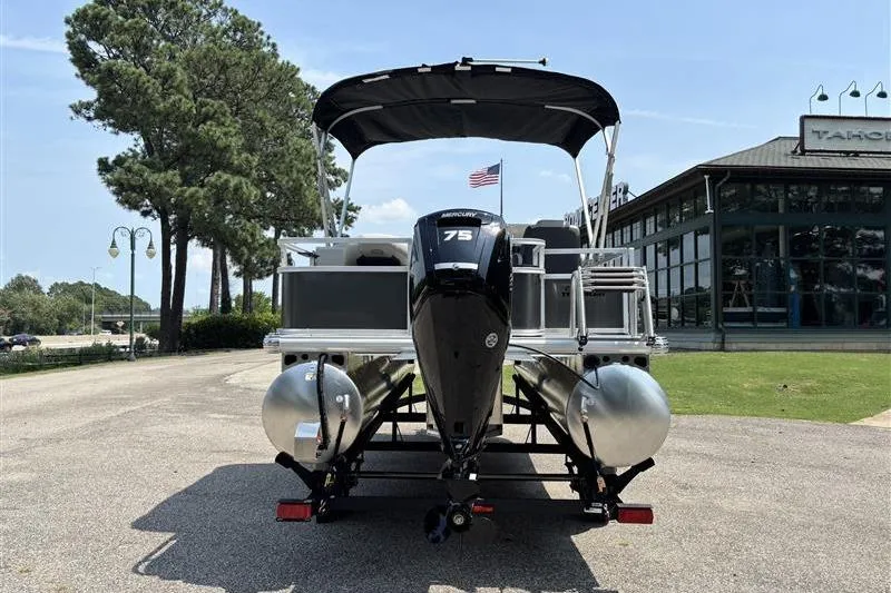 Slide: The Image of 2026 Sun Tracker Bass Buggy 18 DLX pontoon boat with 75 HP engine, parked outdoors. - 2