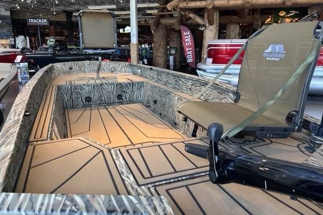 Slide: The Image of 2026 Tracker Grizzly 1650 T Prairie Wings Edition boat interior with camo design in showroom. - 3