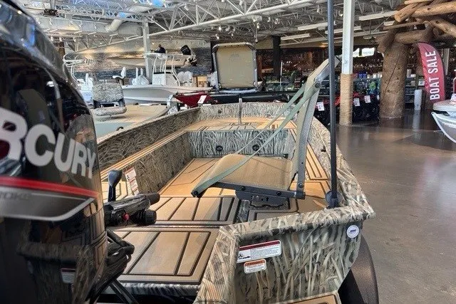 Slide: The Image of 2026 Tracker Grizzly 1650 T Prairie Wings Edition boat displayed in showroom with camo design. - 2