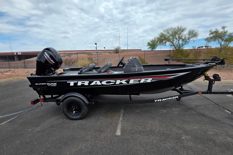 The Image of 2026 Tracker Super Guide V-16 SC boat on trailer, parked outdoors under cloudy sky. - 0