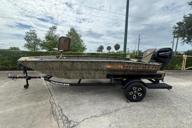 Slide: The Image of 2026 Tracker Grizzly 1756 T Marsh boat on trailer, camo design, parked outdoors. - 48