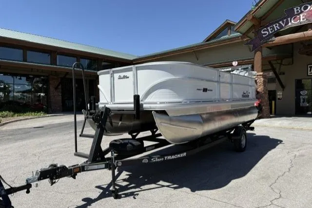 Slide: The Image of 2026 Sun Tracker Party Barge 18 DLX pontoon boat on trailer outside service center. - 2