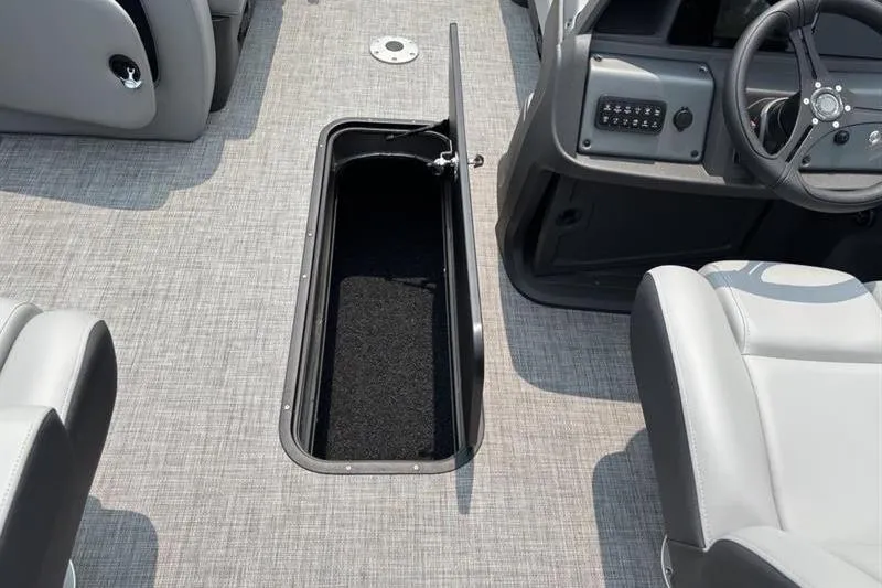 Slide: The Image of 2026 Sun Tracker Party Barge 22 RF XP3 interior with open storage compartment and steering console. - 16