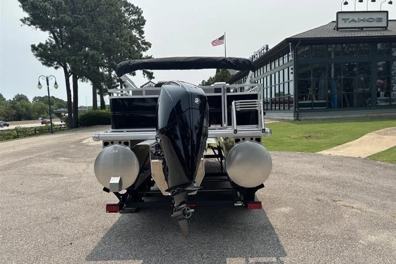 Slide: The Image of 2026 Sun Tracker Party Barge 22 RF XP3 pontoon boat with outboard motor, parked outdoors. - 3