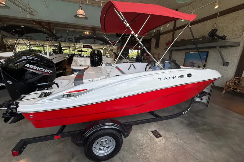 Slide: The Image of 2026 Tahoe T16 boat with red and white design, displayed indoors with a Mercury engine. - 1