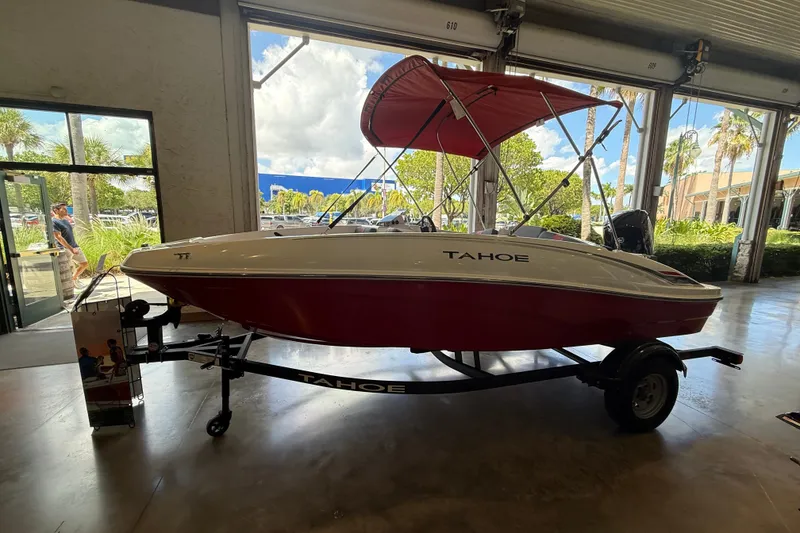 Slide: The Image of 2026 Tahoe T16 boat with red hull and canopy displayed indoors. - 2