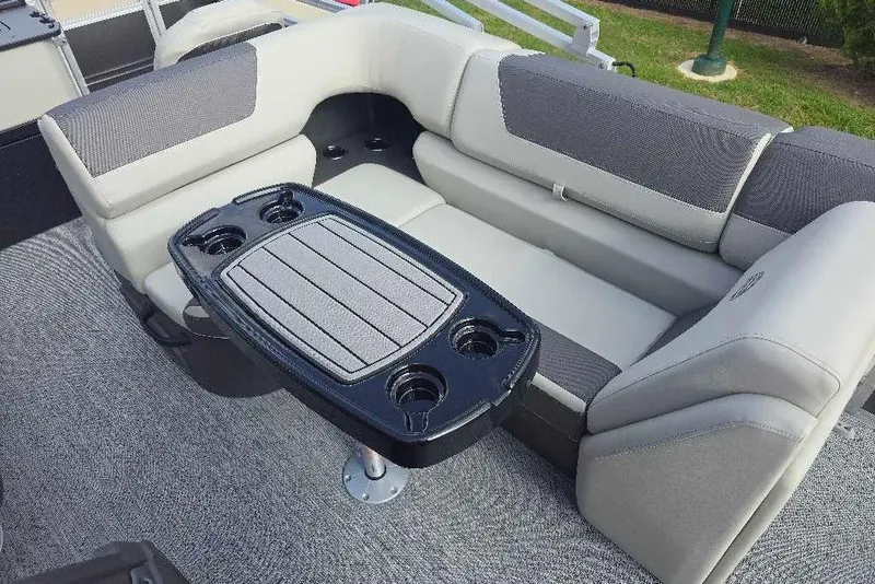 Slide: The Image of 2026 Sun Tracker Fishin' Barge 20 DLX interior with cushioned seating and table with cup holders. - 12
