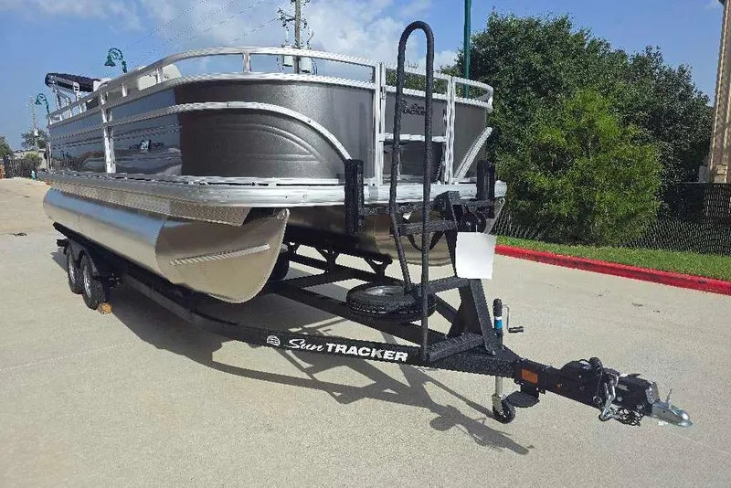 Slide: The Image of 2026 Sun Tracker Fishin' Barge 20 DLX pontoon boat on trailer, parked outdoors. - 3