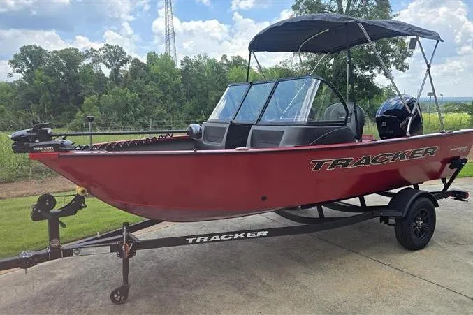 Slide: The Image of 2026 Tracker Pro Guide V-16 WT boat on trailer, red exterior, parked outdoors. - 4