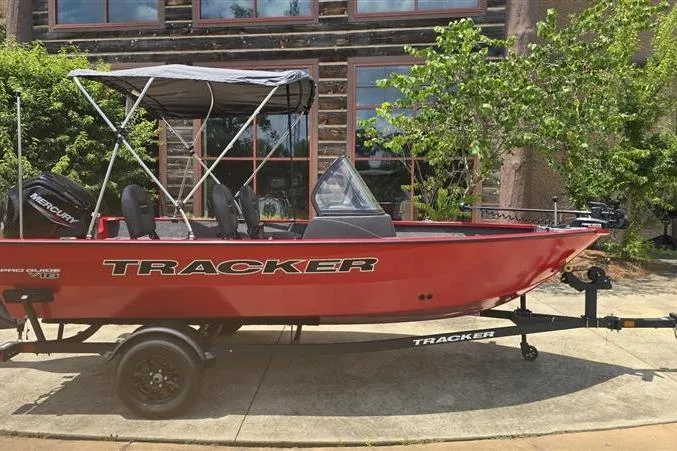The Image of 2026 Tracker Pro Guide V-16 WT boat with canopy on trailer, parked outdoors. - 0