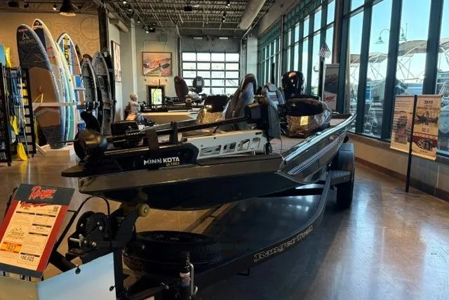The Image of 2026 Ranger RT188P boat displayed indoors with Minn Kota motor, surrounded by surfboards. - 0