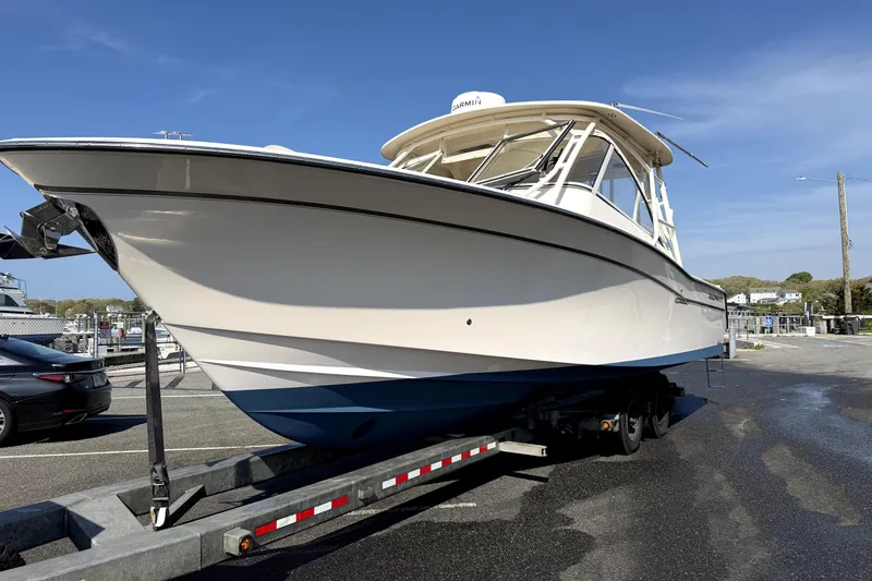 Slide: The Image of 2017 Grady White Freedom 335 boat on trailer, parked outdoors under clear blue sky. - 2