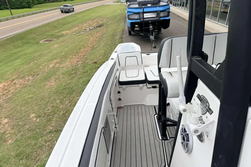 Slide: The Image of 2023 Yamaha Boats 255 FSH Sport E interior with seating and controls, parked near a road. - 9