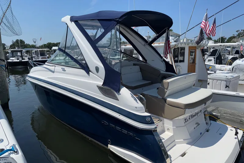 The Image of 2017 Regal 28 Express boat docked, featuring a sleek design and blue canopy. - 0