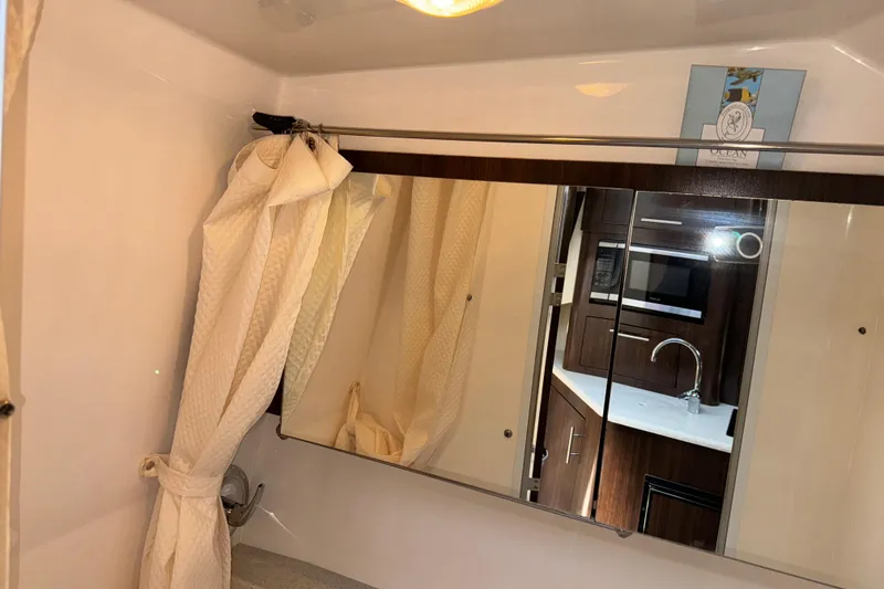Slide: The Image of Interior of 2017 Regal 28 Express boat, featuring a bathroom mirror and kitchenette reflection. - 13