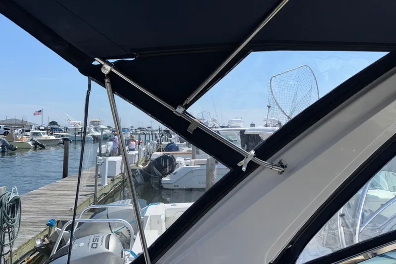 Slide: The Image of 2017 Regal 28 Express boat docked at marina with canopy and fishing net visible. - 28