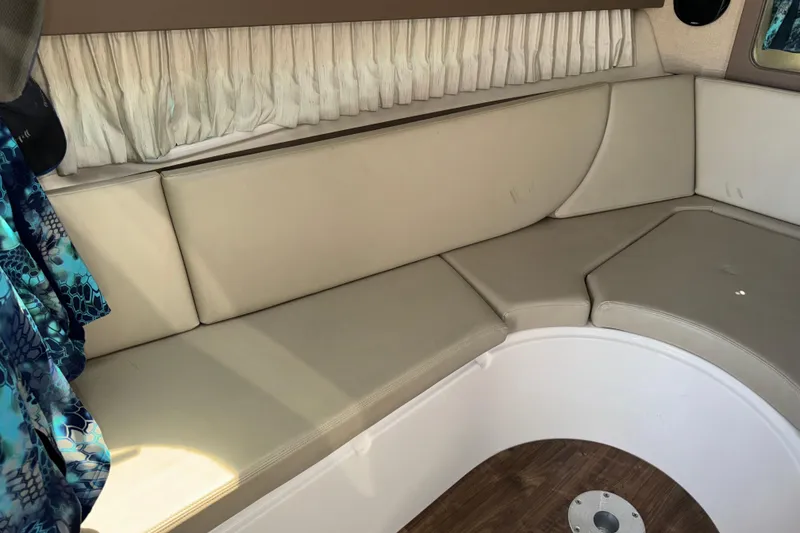 Slide: The Image of Interior seating of a 2017 Regal 28 Express boat with beige cushions and wood flooring. - 48