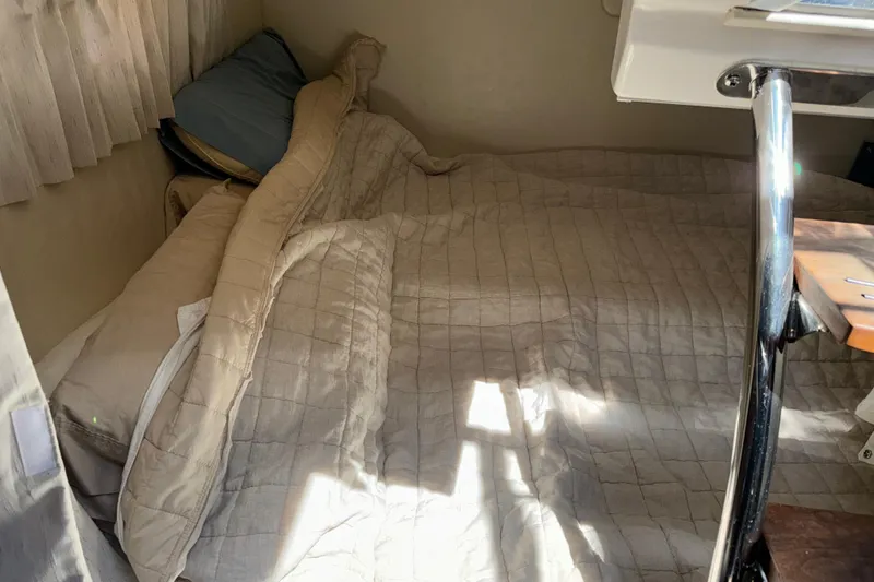 Slide: The Image of Cozy cabin bed inside a 2017 Regal 28 Express boat, with soft bedding and natural light. - 5