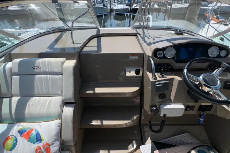 Slide: The Image of 2017 Regal 28 Express boat cockpit with steering wheel and seating, docked at marina. - 64
