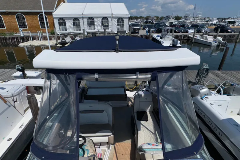 Slide: The Image of 2017 Regal 28 Express boat docked at marina with clear canopy and seating area. - 67