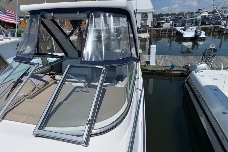 Slide: The Image of 2017 Regal 28 Express boat docked at marina with open windshield and clear canopy. - 68