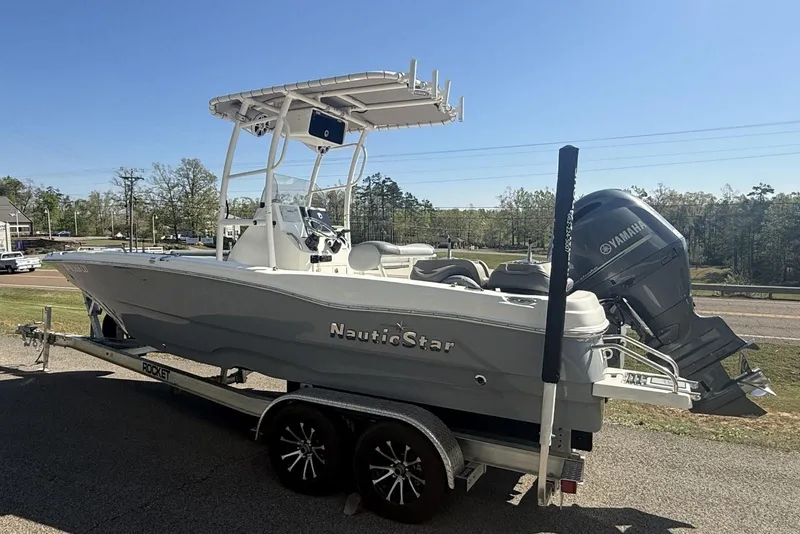 Slide: The Image of 2023 NauticStar 211 Hybrid boat on trailer with Yamaha outboard motor, parked outdoors. - 11