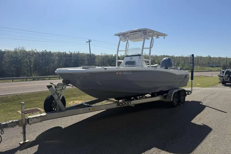 Slide: The Image of 2023 NauticStar 211 Hybrid boat on trailer, parked outdoors under clear sky. - 12