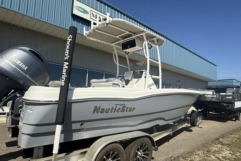 Slide: The Image of 2023 NauticStar 211 Hybrid boat on trailer, displayed outside marine dealership. - 8