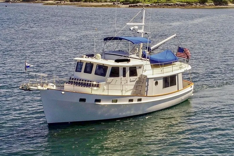 Slide: The Image of 2009 Kadey-Krogen yacht cruising on calm waters with flags and blue canopy. - 2