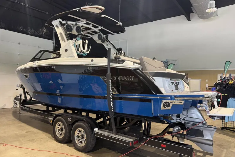 Slide: The Image of 2024 Cobalt R8 Surf boat on trailer in showroom, featuring sleek blue and white design. - 20