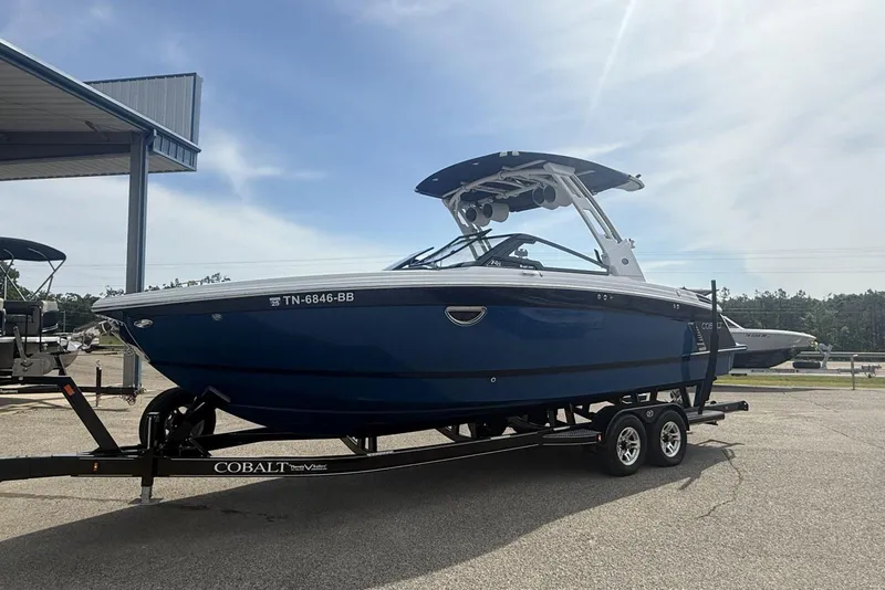 Slide: The Image of 2024 Cobalt R8 Surf boat on trailer, parked outdoors under a clear sky. - 21