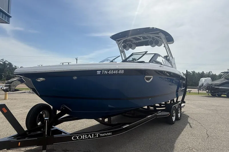 Slide: The Image of 2024 Cobalt R8 Surf boat on trailer, parked outdoors under a clear sky. - 22