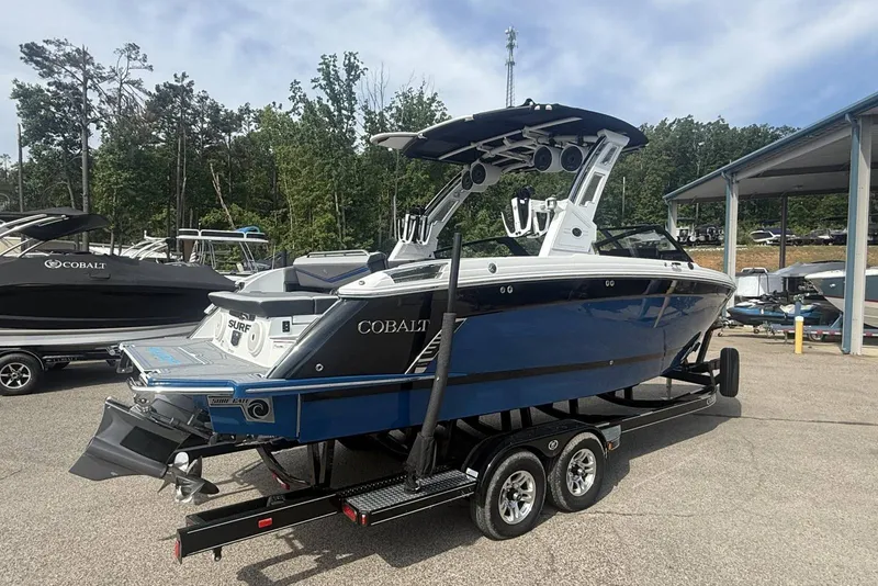 Slide: The Image of 2024 Cobalt R8 Surf boat on trailer, blue and white, parked outdoors. - 3