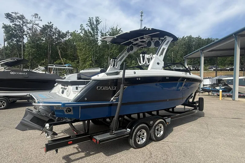 Slide: The Image of 2024 Cobalt R8 Surf boat on trailer, blue and white design, parked outdoors. - 4