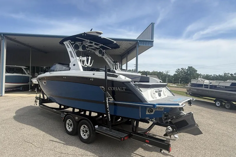Slide: The Image of 2024 Cobalt R8 Surf boat on trailer, blue and white, parked outdoors. - 6