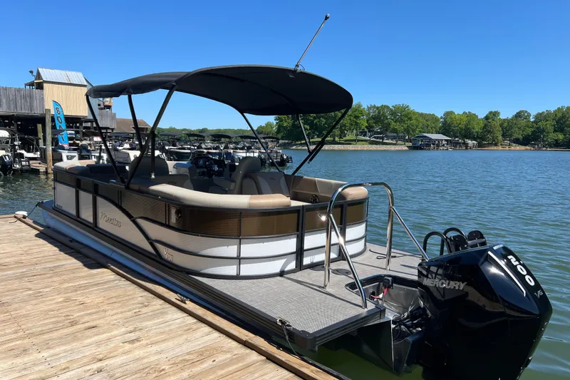 Slide: The Image of 2026 Manitou 23 Aurora LE RF pontoon boat docked on a sunny lake. - 2